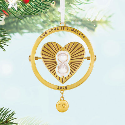 Gold metal anniversary ornament with heart and spinning hourglass, “Our Love Is Timeless” message, and interchangeable year charms.