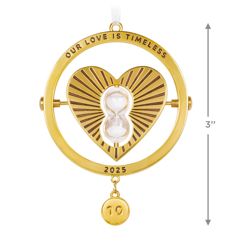 Gold metal anniversary ornament with heart and spinning hourglass, “Our Love Is Timeless” message, and interchangeable year charms.