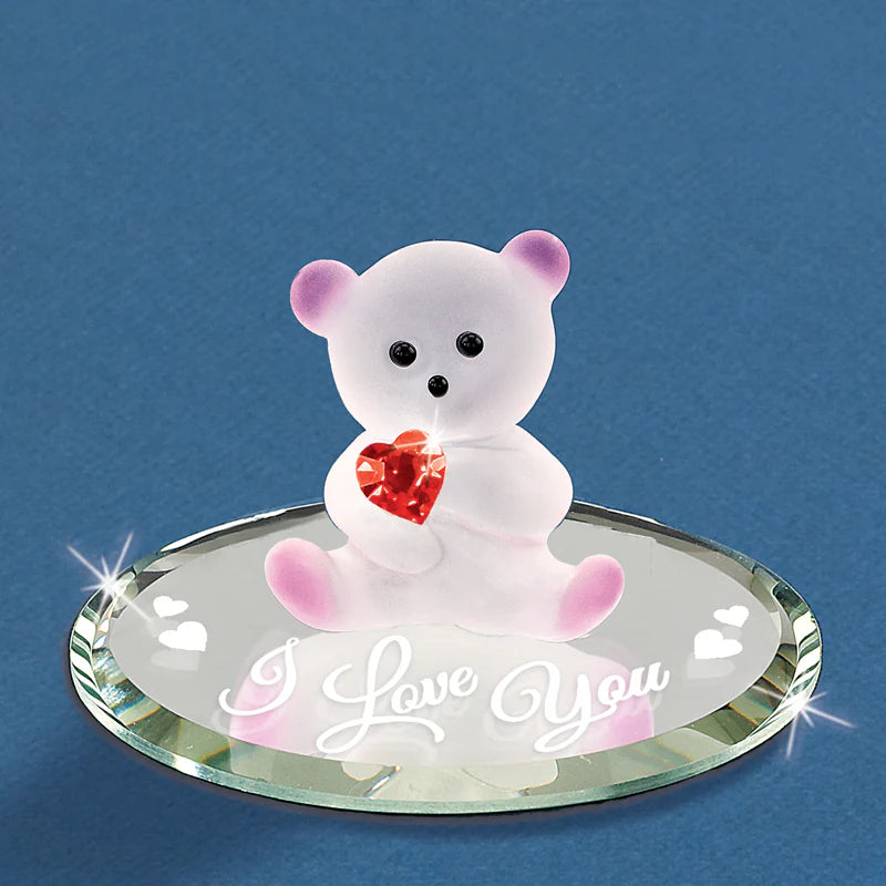 A small, handcrafted bear figurine holding a crystal heart on a beveled glass mirror, accented with genuine crystals.
