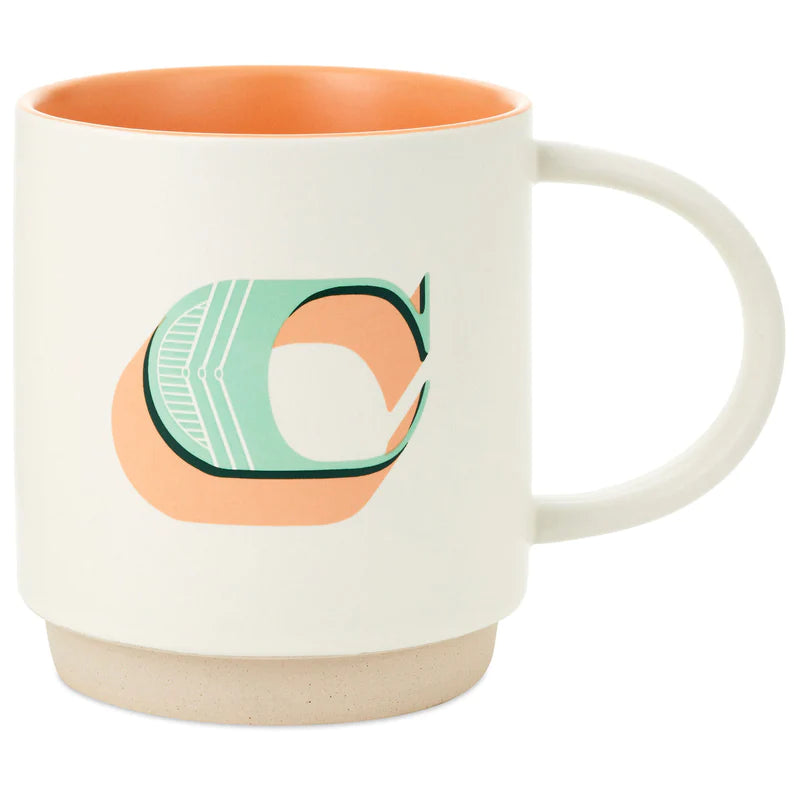 Ceramic monogram mug with patterned letter C, cream background, wide handle, and stackable recessed base.

