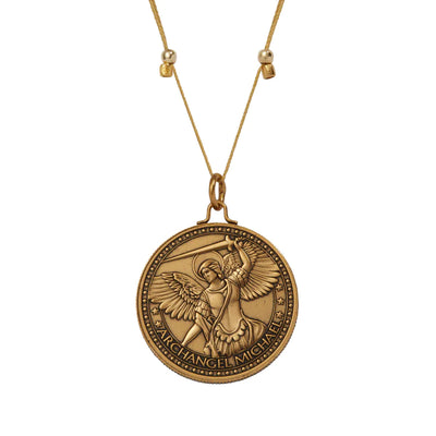 The pendant is gold and shaped like a rounded shield. In the center of the pendant is a detailed image of a winged angel.The text "ARCHANGEL MICHAEL" is written around the edge of the pendant in a decorative font.