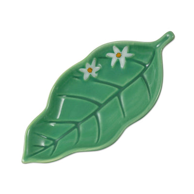 Green ceramic leaf-shaped trinket dish with embossed vein details and small white flowers.