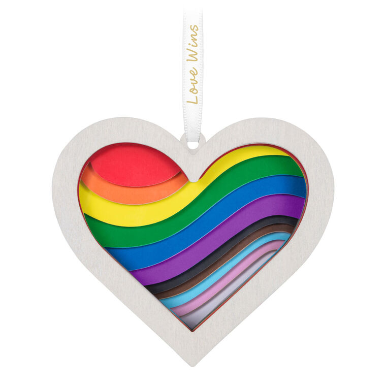 Heart-shaped rainbow papercraft ornament in a whitewashed wood frame with “Love Wins” ribbon for LGBTQIA holiday celebration.