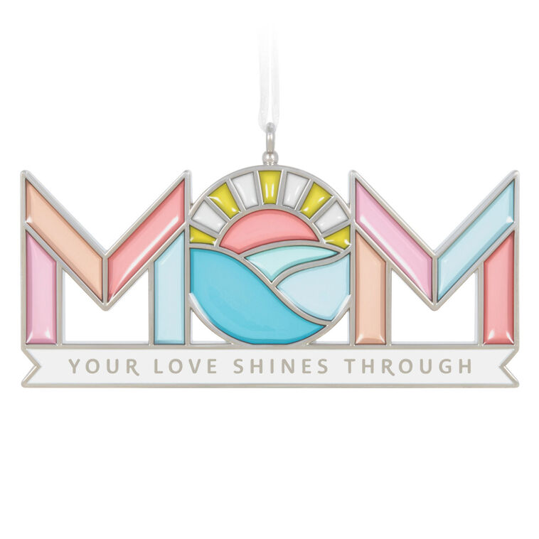 Stained-glass style metal ornament spelling “Mom” with sun and waves in the O, and banner reading “Your love shines through.”