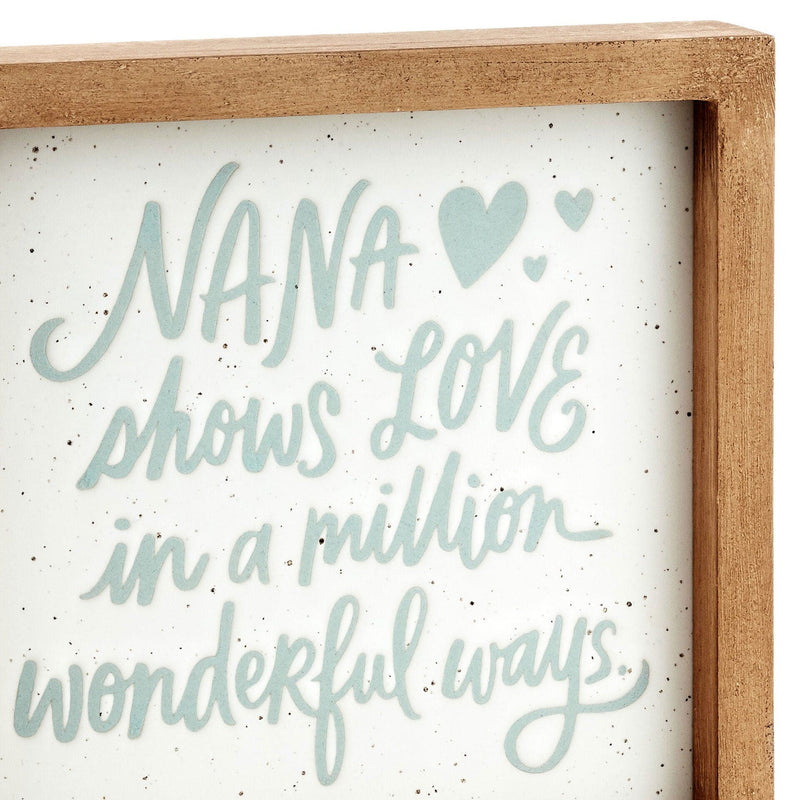 Square ceramic and wood quote sign with blue text that reads "Nana shows love in a million wonderful ways."

