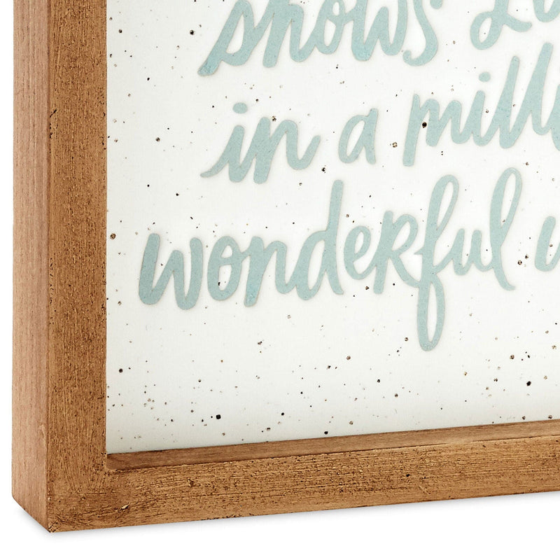 Square ceramic and wood quote sign with blue text that reads "Nana shows love in a million wonderful ways."


