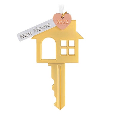 Gold metal key ornament shaped like a house with a pink heart and “New Home” banner charm, for new homeowners.
