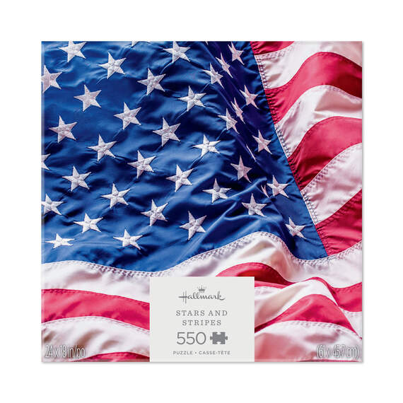 Hallmark 550-piece puzzle showing a close-up of the rippling American flag with red, white, and blue stars and stripes.

