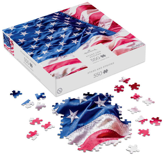 Hallmark 550-piece puzzle showing a close-up of the rippling American flag with red, white, and blue stars and stripes.

