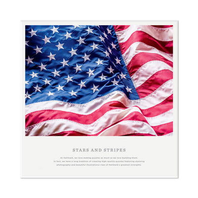 Hallmark 550-piece puzzle showing a close-up of the rippling American flag with red, white, and blue stars and stripes.

