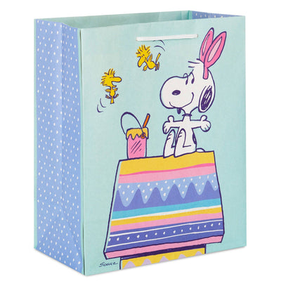 Snoopy wearing bunny ears and painting an Easter egg on a Hallmark 9.6" Peanuts Snoopy The Easter Beagle Medium Gift Bag.  pen_spark