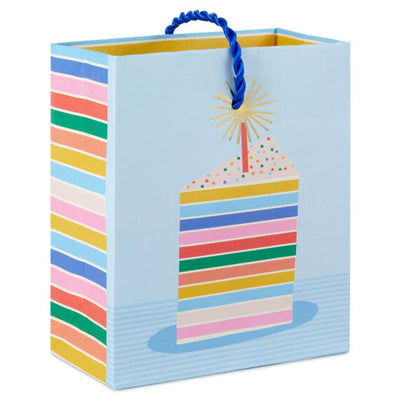 Mini gift bag with colorful layered cake slice design, gold foil accents, and pale blue background with twisted cord handles.

