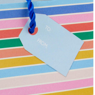 Mini gift bag with colorful layered cake slice design, gold foil accents, and pale blue background with twisted cord handles.

