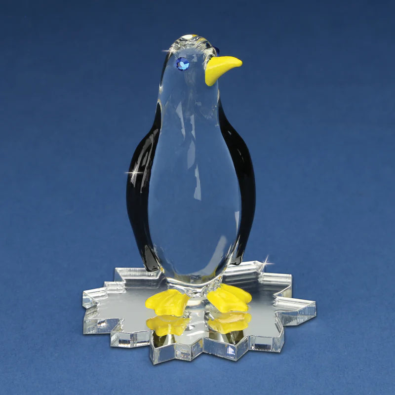 Handcrafted glass penguin with yellow accents on ice-shaped base, accented with Genuine Crystals.