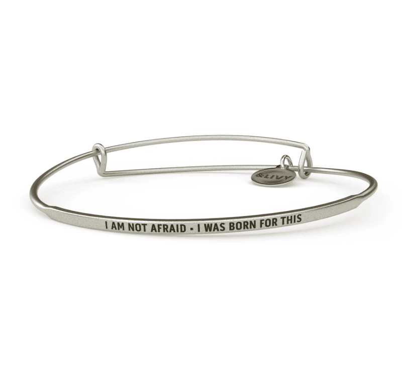 Silver bangle bracelet with the words "I am not afraid - I was born for this" engraved on it. The lettering is cursive.