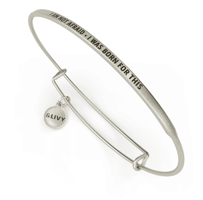 Silver bangle bracelet with the words "I am not afraid - I was born for this" engraved on it. The lettering is cursive.