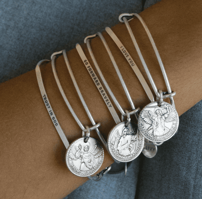 Stack of silver bangle bracelets with words engraved on them. Words include "I LOVE YOU". 