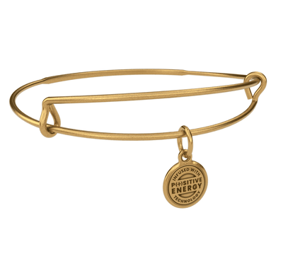 Gold bangle bracelet with a gold charm. The charm is round and features the text “INFUSED WITH  POSITIVE ENERGY TECHNOLOGY”. 