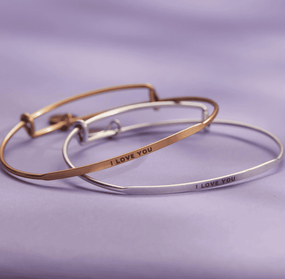 Gold bangle bracelet with the words "I love you" engraved on it.