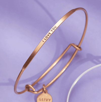 Gold bangle bracelet with the words "I love you" engraved on it.