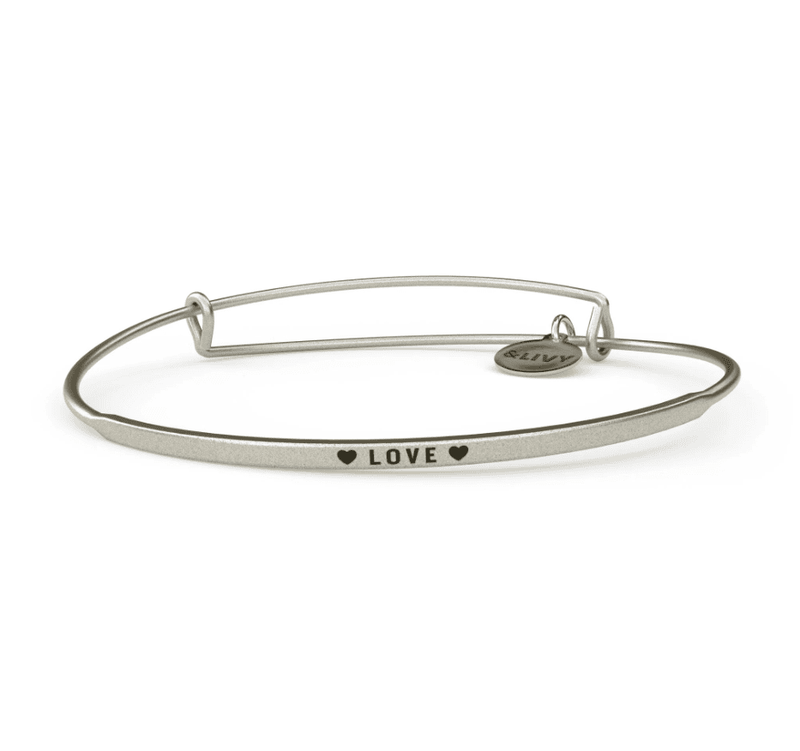 Silver bangle bracelet with a heart-shaped charm and the word "love" engraved on it. 