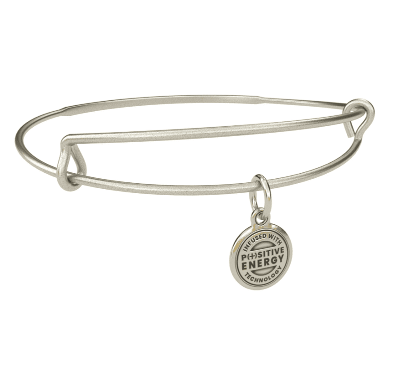 Silver bangle bracelet with a gold charm. The charm is round and features the text “INFUSED WITH POSITIVE ENERGY TECHNOLOGY”.