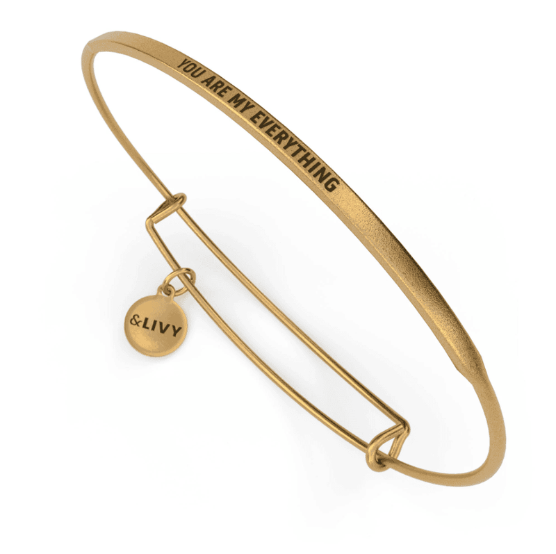 Gold bangle bracelet with the words "You are my everything" engraved on it.