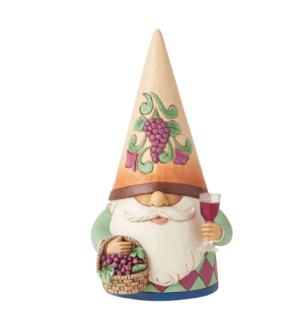 A wooden gnome holding a glass of wine and a basket of grapes