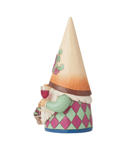 A wooden gnome holding a glass of wine and a basket of grapes