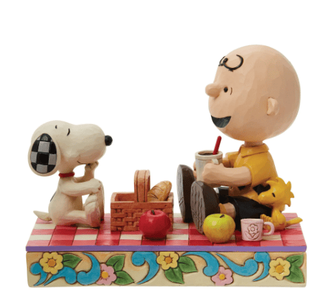 Jim Shore figurine of Charlie Brown, Snoopy, and Woodstock enjoying a picnic on a red quilted blanket, hand-painted in folk art style.