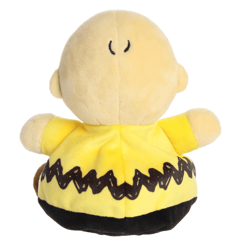 A small plush Charlie Brown doll with a round head and soft yellow shirt, part of the Palm Pals collection.