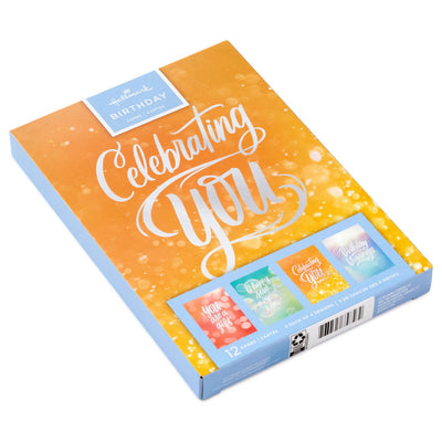 Boxed birthday cards with colorful soft-focus backgrounds, script lettering, silver foil accents, and envelopes, four bright cheerful designs.

