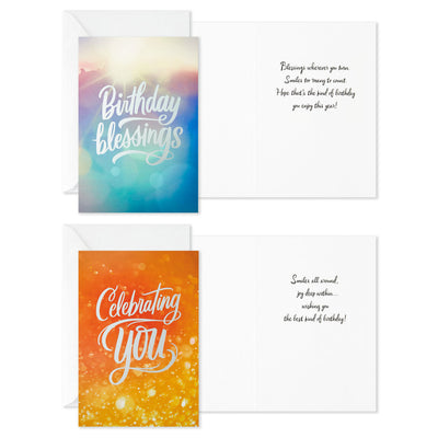 Boxed birthday cards with colorful soft-focus backgrounds, script lettering, silver foil accents, and envelopes, four bright cheerful designs.
