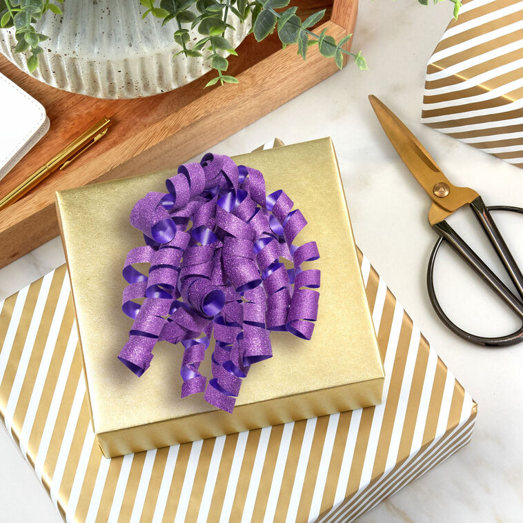Hallmark purple curly gift bow with glittery corkscrew ribbon strands and self-adhesive backing, ideal for wrapped birthday gifts.