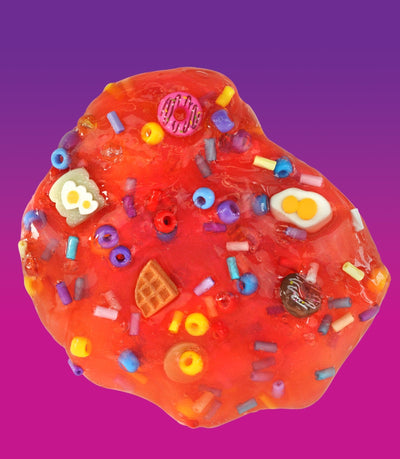 Crazy Aaron’s Sunny Side Up red slime with egg, donut, and croissant charms for fun sensory play that’s squishy, stretchy, and savory-sweet