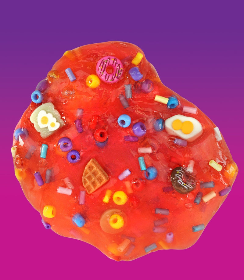 Crazy Aaron’s Sunny Side Up red slime with egg, donut, and croissant charms for fun sensory play that’s squishy, stretchy, and savory-sweet