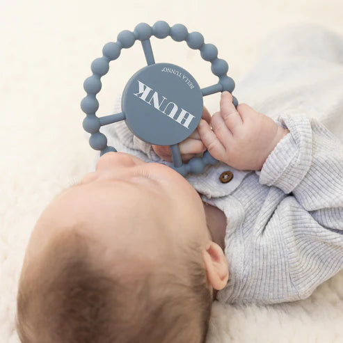 Round silicone teether with the word "Hunk" printed on it, designed for babies with easy grip and textured surface.