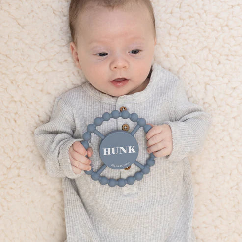Round silicone teether with the word "Hunk" printed on it, designed for babies with easy grip and textured surface.