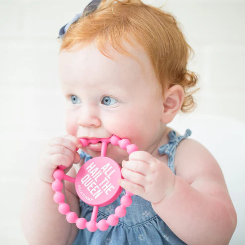 Circular silicone baby teether with "All Hail the Queen" phrase, textured edge, easy to grip and chew for teething relief.