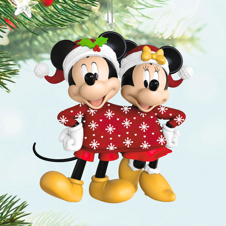 Mickey and Minnie wearing Santa hats and sharing a red Christmas sweater with snowflakes and hearts, Disney ornament.

