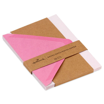 Pink envelopes with white and pink brushstroke flap design and scattered gold foil dot accents, featuring pointed flaps.
