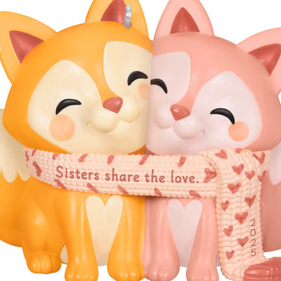 2025 Christmas ornament with two foxes snuggled in a heart-patterned scarf, celebrating sisterly love

