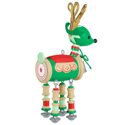 Green reindeer ornament made of red and green thread spools with gold scissors antlers, button tail, and silver thimble bell

