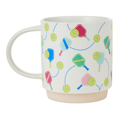 White ceramic pickleball mug with colorful paddle and ball icons, oversized handle, and stackable recessed base