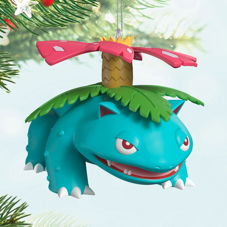 Hallmark Keepsake Pokémon Venusaur ornament with pink blossom on its back, blue-green body, red eyes, and festive Christmas style.