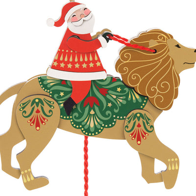 Wooden pull-string ornament of Santa riding a lion with moving reins and legs, inspired by jumping jack toys
