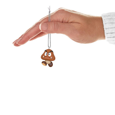 Hallmark Keepsake Mini Nintendo Super Mario Goomba ornament—brown mushroom-like enemy with sharp teeth, large eyes, oval feet, and angry eyebrows
