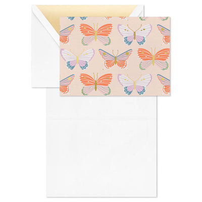 Blank note cards with colorful butterfly illustrations and gold foil accents on a soft peach background.