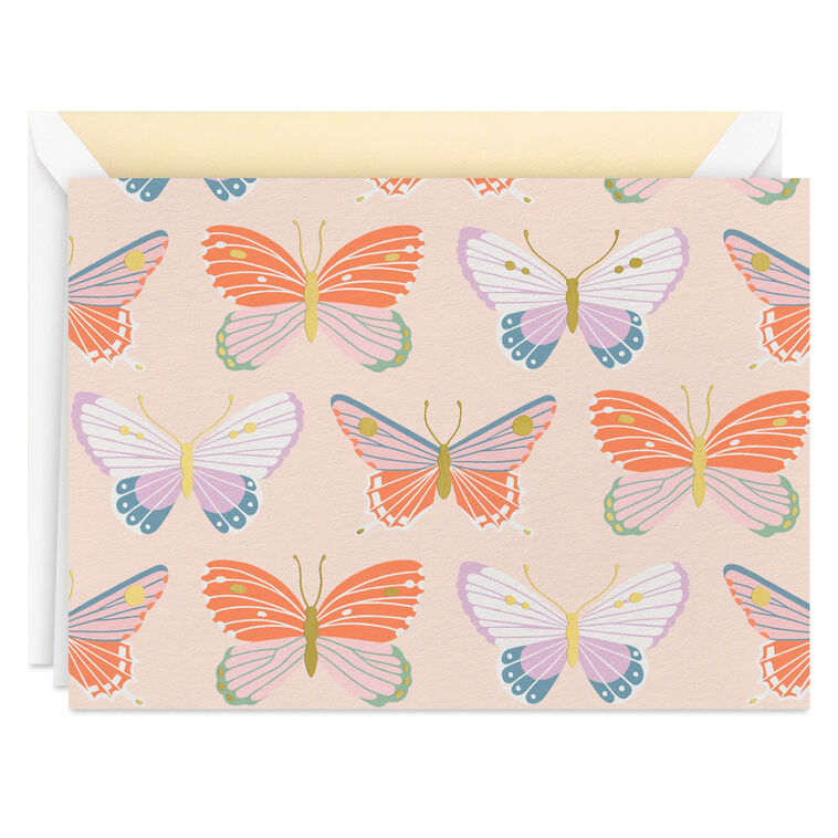 Blank note cards with colorful butterfly illustrations and gold foil accents on a soft peach background.