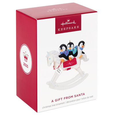 Christmas ornament of playful penguins on a sparkling rocking horse with red and white monogrammed saddle